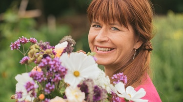 Moderatorin Sabrina Nitsche schneidet im Querbeet-Garten einen sommerlichen Blumenstrauß. | Bild: BR/Lisa Hinder