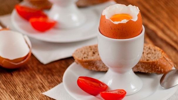 Frühstückei steht in einem Eierbecher auf einem Teller mit einer Kirschtomate | Bild: mauritius images / Libor Vrska / Alamy / Alamy Stock Photos