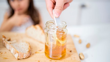 Ein Glas mit Honig steht auf einem Tisch | Bild: mauritius-images