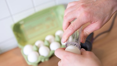 Ein Mann pikst ein Ei an | Bild: dpa/picture alliance