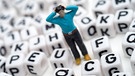 Eine verzweifelte Männerfigur steht inmitten von Buchstabenwürfeln | Bild: picture-alliance/dpa