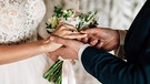 Heiratsmonat Mai: Der Bräutigam steckt der Braut den Hochzeitsring an. | Bild: stock.adobe.com/Viktar Vysotski